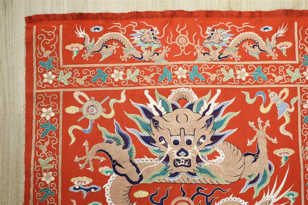 A early 20th century Chinese red felt square panel embroidered with a central motif of a dragon, width 86cm height 84cm